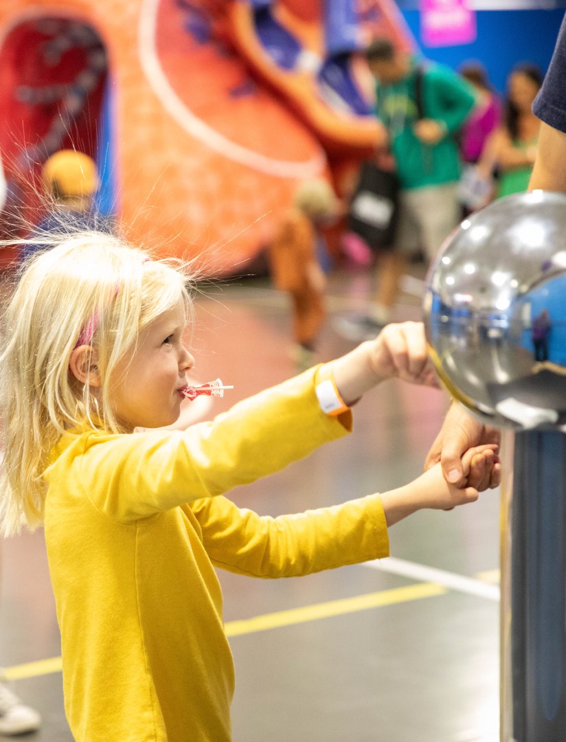 Little girl with static hair touching a ball